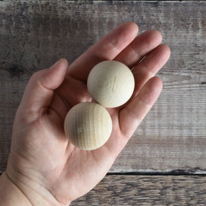 Hand holding a 40mm wooden ball in solid beech